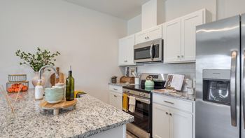 A kitchen with a granite countertop and stainless steel appliances at The Mark Townhomes Apartments, Virginia